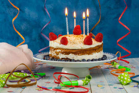birthday cake with cream and raspberry sponge cake with candles and streamersの写真素材