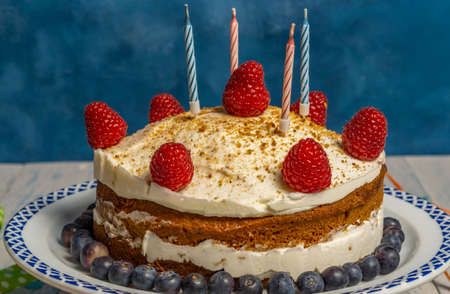 birthday cake with cream and raspberry sponge cake with candles and streamersの写真素材