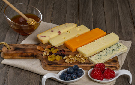 assorted cheese board with honey, nuts, blueberries and raspberries on wooden backgroundの写真素材