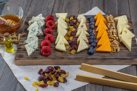 assorted cheese board with honey, nuts, blueberries and raspberries on wooden backgroundの写真素材