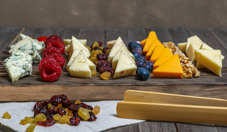 assorted cheese board with honey, nuts, blueberries and raspberries on wooden backgroundの写真素材