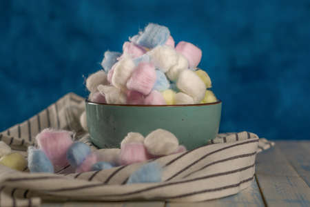 colored cotton balls in various containers on a blue backgroundの写真素材