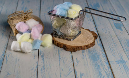 colored cotton balls in various containers on a blue backgroundの写真素材
