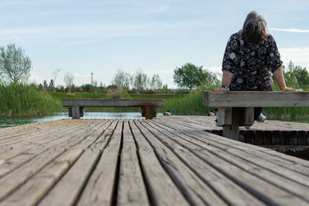 young couple sitting on the shore of a lake looking at the waterの写真素材