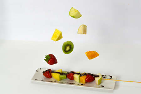 skewer of fruits suspended in the air on a white backgroundの写真素材