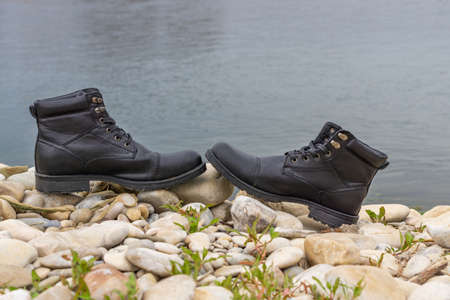 men's boots, black leather with river and trees in the backgroundの写真素材