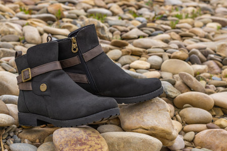 women's boots, brown and black leather on river bankの写真素材