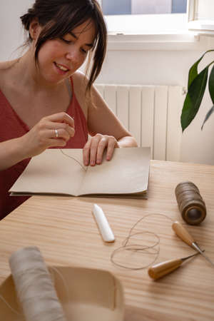 young artisan woman working in her ecological notebook workshopの写真素材