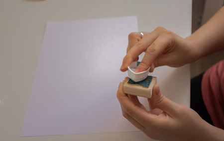 woman's hands placing a sustainable packaging stamp on a blank sheet of paperの写真素材
