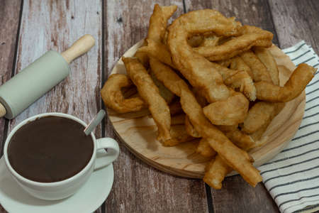 cup of hot chocolate with freshly made churros on wooden background typical spanish breakfast on holidaysの写真素材