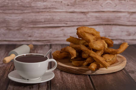 cup of hot chocolate with freshly made churros on wooden background typical spanish breakfast on holidaysの写真素材