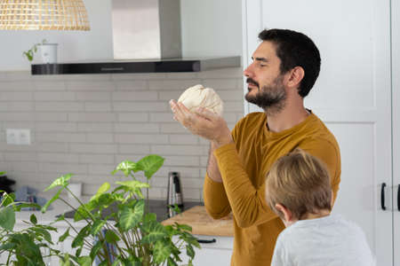 young man making homemade bread with his son in his home kitchenの写真素材