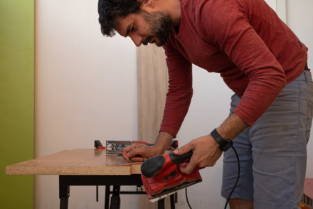 young man using carpenter's power tools making wooden furniture in his homeの写真素材