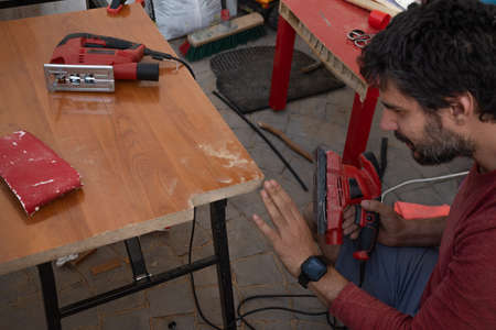 young man using carpenter's power tools making wooden furniture in his homeの写真素材