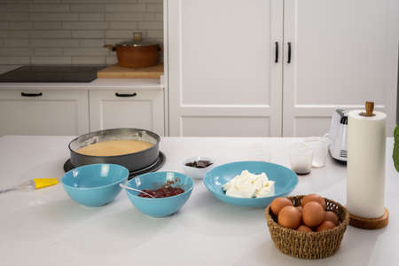 process of making a strawberry cake in a white kitchen all ingredients
