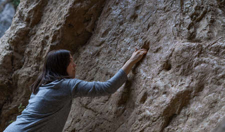 young girl learning rock climbing in high mountain with blue sweater, black tights and boots.の写真素材