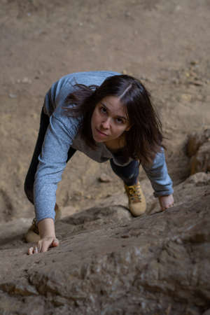 young girl learning rock climbing in high mountain with blue sweater, black tights and boots.の写真素材
