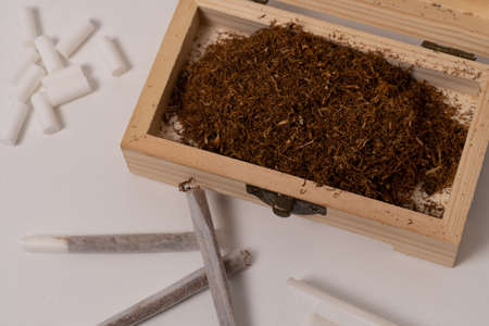 Hand rolling tobacco on a wood table and cigarettesの写真素材