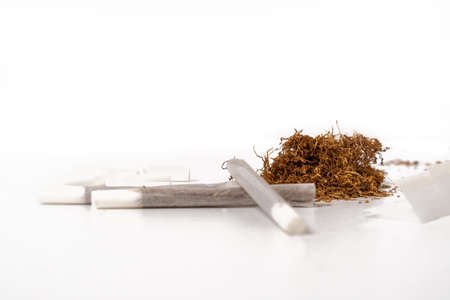 Hand rolling tobacco on a wood table and cigarettes