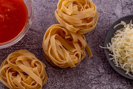 homemade vegan pasta with zucchini, onion, peppers and orange on a blue plate with a gray backgroundの写真素材