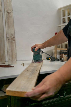 hands with electric screwdriver screwing screws into woodの写真素材