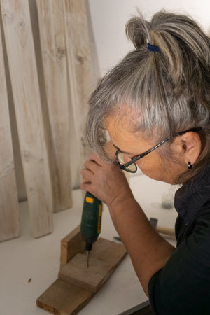 hands with electric screwdriver screwing screws into woodの写真素材