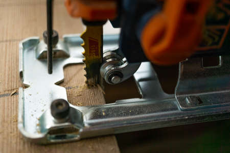 hands with electric screwdriver screwing screws into woodの写真素材
