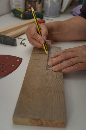 hands with electric screwdriver screwing screws into wood