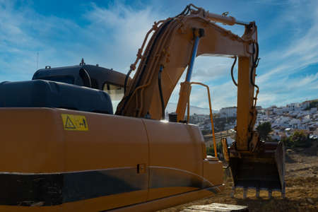 large yellow excavator working on the construction site moving earth