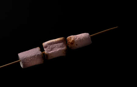 skewer of sweet marshmallows on a white backgroundの写真素材