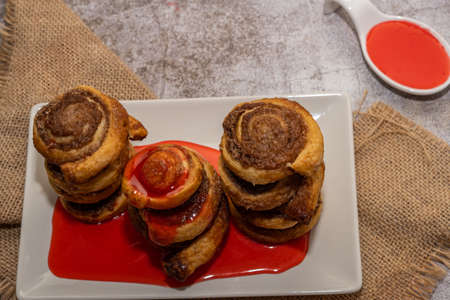 whole cinnamon and sugar roll ready to cut and bake on a white baking trayの写真素材