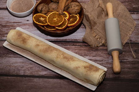 whole cinnamon and sugar roll ready to cut and bake on a white baking trayの写真素材