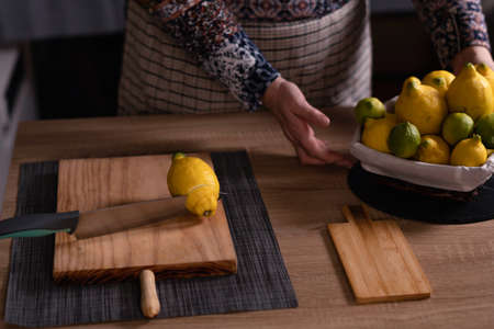 woman's hands cutting lemons and limes on a wooden boardの写真素材