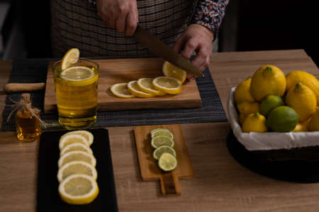woman's hands cutting lemons and limes on a wooden board