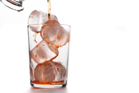 crystal glass with ices pouring red cocktail on white background and copy spaceの写真素材