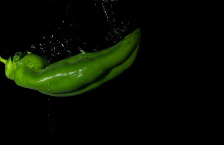 green bell pepper in water with splash on black background.isolated with bubblesの写真素材