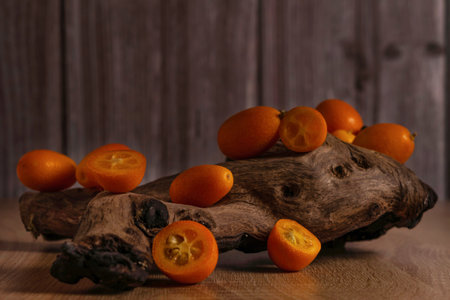 close-up of small Chinese oranges or Kumquat (Citrus sinensis) on a root of a tree on a wooden tableの写真素材
