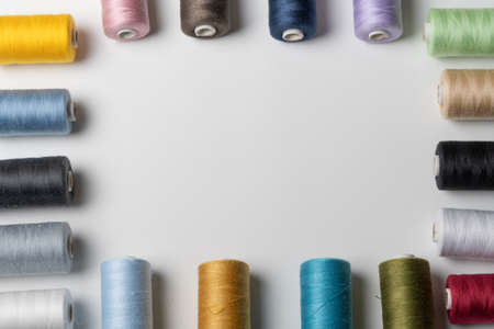 spools of colored sewing thread on white background with copy spaceの写真素材