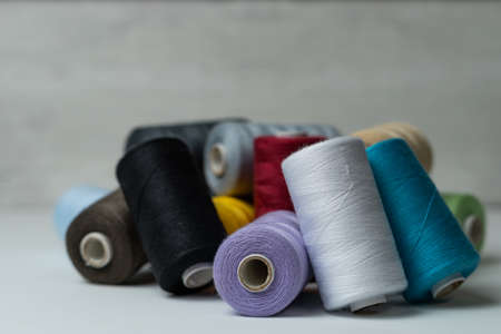 spools of colored sewing thread on white background with copy space