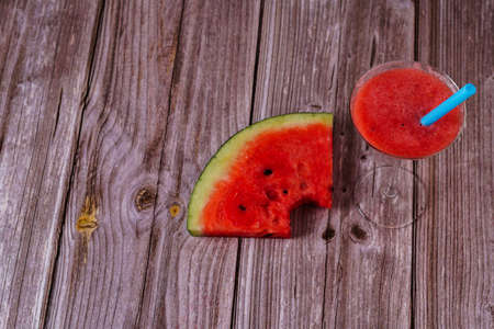 cocktail glass with watermelon juice and slices of fresh watermelon on a wooden tableの写真素材