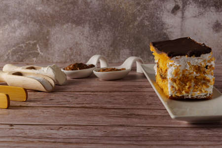puff pastry cake with cream and almonds covered with chocolate with spoons with its ingredients and...