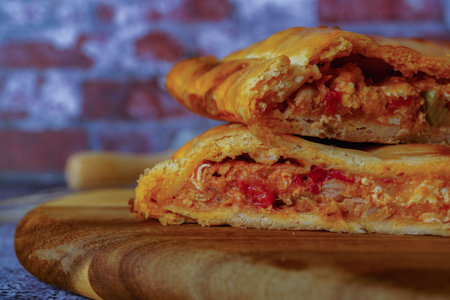 close-up of the filling of a tuna empanada with its ingredients on a wooden board with a brick...
