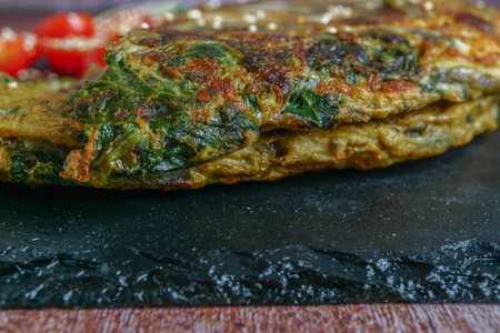 close-up of a freshly made spinach tortilla on a black slate plate