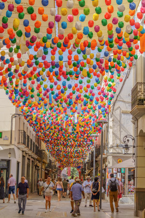 08/31/2022 Ronda,Malaga,Andalucia,Spain people walking along the calle de la bola at the feria de ronda with colored lanternsのeditorial素材