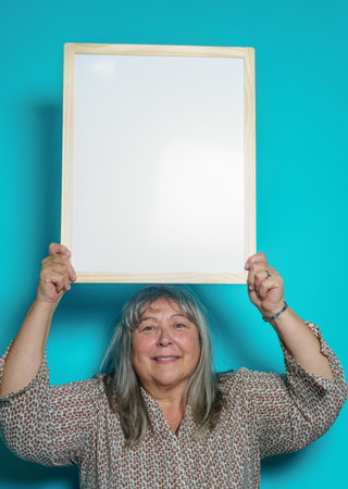 older white-haired woman holding a white board to paste text onの写真素材