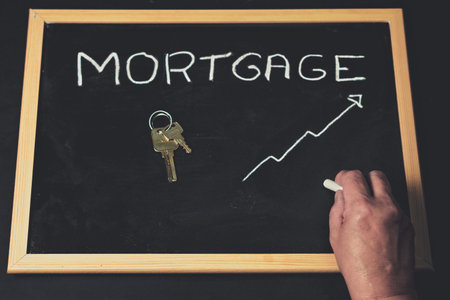 woman's hand with house keys , price of mortgages on a blackboard written with chalkの写真素材