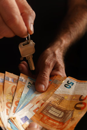 woman handing over money and man handing over the keys to a house, concept of buying and selling