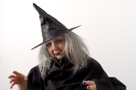 close-up of a white-haired witch in a black hat and costume on a white background