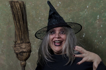 close-up of a white-haired witch with her broom against an abstract background