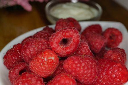 raspberries in a white ceramic bowl on a wooden table